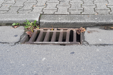 rechteckiger Sinkkasten am Straßenrand.
